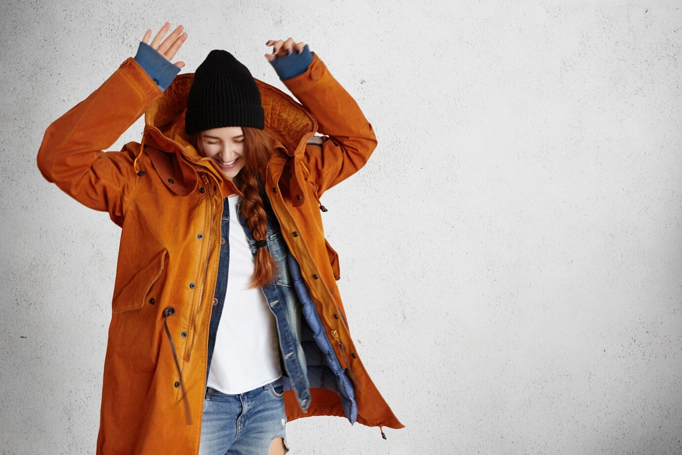 fashionable-young-woman-wearing-red-winter-coat-black-hat-ragged-jeans-raising-hands-air_273609-9062